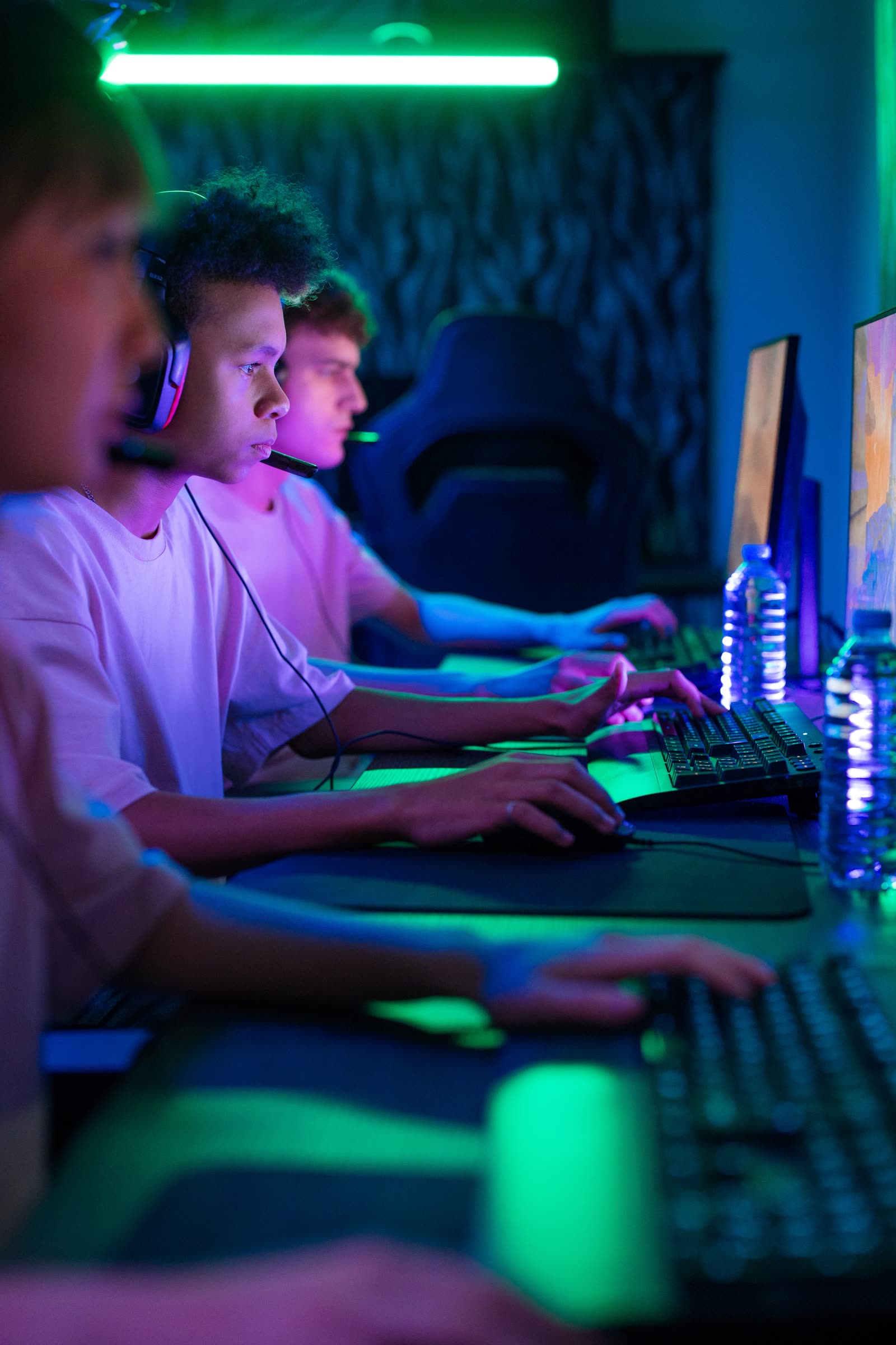 A dim row of headset-wearing players leaning into their screens in the darker back wing